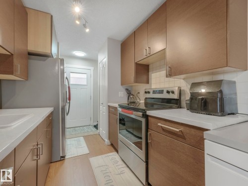 Kitchen with stainless steel appliances, a textured ceiling, light wood finished floors, and decorative backsplash - 13271 47 Street, Edmonton, AB - Indoor Photo Showing Kitchen