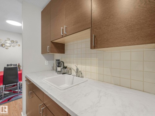 Kitchen with decorative backsplash, light wood-type flooring, and light stone counters - 13271 47 Street, Edmonton, AB - Indoor Photo Showing Kitchen