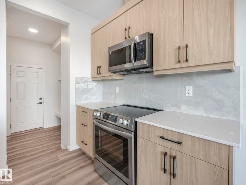 Kitchen with stainless steel appliances, light wood finish cabinetry, backsplash, and light stone countertops - 20506 16A Avenue, Edmonton, AB - Indoor Photo Showing Kitchen