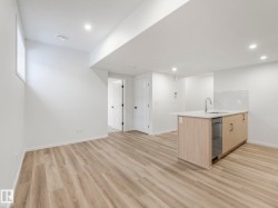 Bar with light wood finish cabinets, light wood-type flooring, dishwasher, recessed lighting, and light stone countertops - 