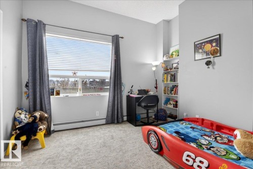 Bedroom with light carpet, baseboard heating, and a textured ceiling - 105 9707 105 Street, Edmonton, AB - Indoor Photo Showing Bedroom
