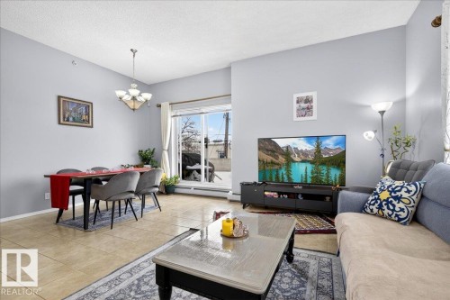 Living room featuring suspended lighting, tile patterned flooring, a textured ceiling, and a baseboard radiator - 105 9707 105 Street, Edmonton, AB - Indoor Photo Showing Living Room