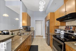 Kitchen featuring stainless steel appliances, backsplash, pendant lighting, dark stone counters, and light tile patterned flooring - 