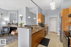 Kitchen featuring light tile patterned floors, dark stone countertops, decorative light fixtures, a fireplace, and wood finish cabinets - 