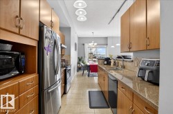 Kitchen with a textured ceiling, black appliances, dark stone countertops, light tile patterned floors, and range hood - 