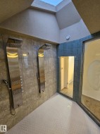 Bathroom featuring tile walls, vaulted ceiling, and a walk in shower - 