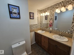 Full bathroom with decorative backsplash, double vanity, and dark tile patterned floors - 