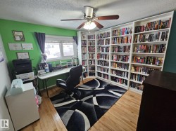 Office with light wood-style flooring, a ceiling fan, a textured ceiling, and bookshelves - 