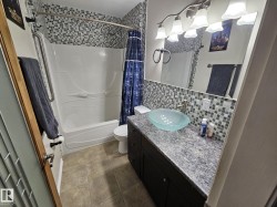 Bathroom with vanity, shower / bath combo with shower curtain, and backsplash - 