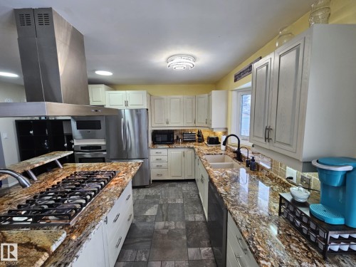 Kitchen with island range hood, black appliances, and light stone counters - 8512 131 Avenue, Edmonton, AB - Indoor Photo Showing Kitchen With Double Sink With Upgraded Kitchen