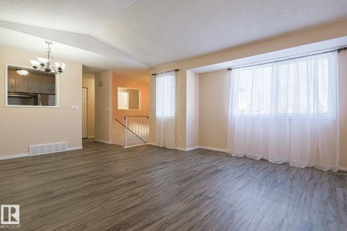 Unfurnished living room with suspended lighting and wood finished floors - 1526 69 Street Nw, Edmonton, AB - Indoor Photo Showing Other Room
