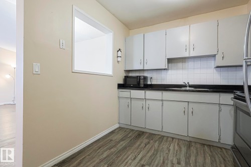 Kitchen featuring dark countertops, stainless steel range oven, decorative backsplash, and dark wood-style flooring - 1526 69 Street Nw, Edmonton, AB - Indoor Photo Showing Kitchen