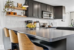 Kitchen featuring a peninsula, a kitchen bar, stainless steel appliances, tasteful backsplash, and open shelves - 