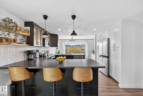 Kitchen with a kitchen breakfast bar, dark countertops, a peninsula, hanging light fixtures, and stainless steel appliances - 23509A Twp Road 484, Rural Leduc County, AB - Indoor