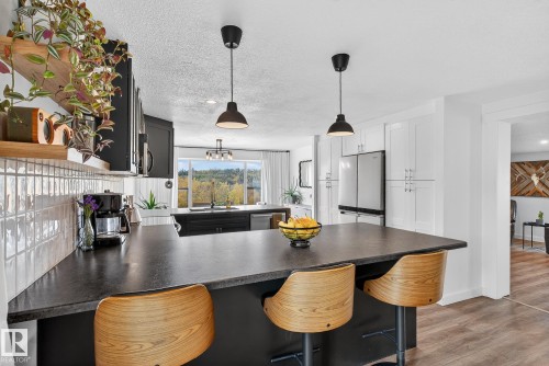 Kitchen featuring a kitchen breakfast bar, a peninsula, dark countertops, pendant lighting, and a textured ceiling - 23509A Twp Road 484, Rural Leduc County, AB - Indoor