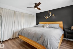 Bedroom featuring a ceiling fan, wood finished floors, and an accent wall - 