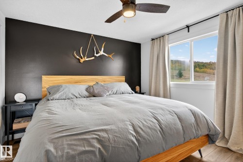Bedroom featuring wood finished floors, ceiling fan, and an accent wall - 23509A Twp Road 484, Rural Leduc County, AB - Indoor Photo Showing Bedroom