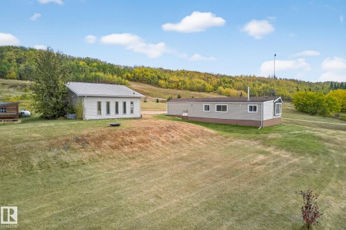 Rear view of property featuring a lawn and a forest view - 23509A Twp Road 484, Rural Leduc County, AB - Outdoor