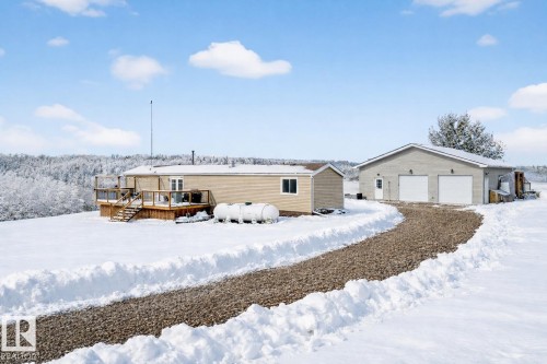 Snow covered back of property featuring a deck and an outbuilding - 23509A Twp Road 484, Rural Leduc County, AB - Outdoor