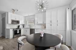 Kitchen featuring stainless steel appliances, white cabinets, dark wood-type flooring, suspended lighting, and tasteful backsplash - 