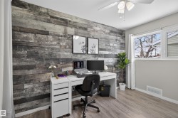 Office featuring wood walls, wood finished floors, a ceiling fan, and an accent wall - 