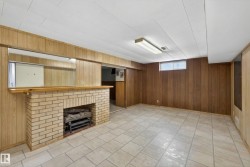 Basement featuring wood walls, a fireplace, and light tile patterned floors - 