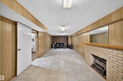 Finished basement featuring a fireplace, wood walls, and light tile patterned floors - 
