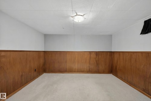Carpeted spare room featuring wooden walls and wainscoting - 7719 71 Avenue, Edmonton, AB - Indoor Photo Showing Other Room