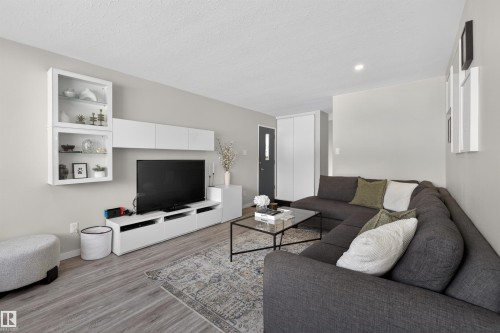 Living room with light wood finished floors and a textured ceiling - 7719 71 Avenue, Edmonton, AB - Indoor Photo Showing Living Room