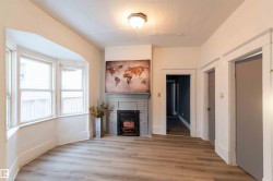 Unfurnished living room featuring light wood-style floors, a brick fireplace, and a textured ceiling - 