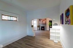 Unfurnished living room featuring a fireplace, arched walkways, plenty of natural light, and wood finished floors - 