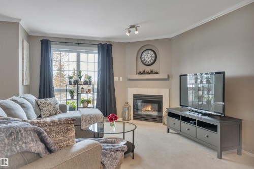 Carpeted living room with ornamental molding and a tile fireplace - 203 35 Sir Winston Churchill Avenue, St. Albert, AB - Indoor Photo Showing Living Room With Fireplace