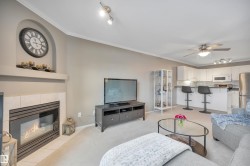 Living area featuring track lighting, ornamental molding, ceiling fan, a tiled fireplace, and light colored carpet - 