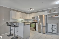 Kitchen featuring stainless steel appliances, open shelves, white cabinets, a breakfast bar, and ornamental molding - 