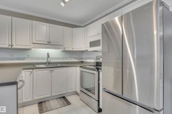 Kitchen with stainless steel appliances, white cabinets, light tile patterned floors, ornamental molding, and decorative backsplash - 