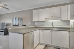Kitchen with white cabinetry, dishwasher, a peninsula, crown molding, and tasteful backsplash - 