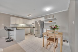 Kitchen with stainless steel appliances, a kitchen breakfast bar, white cabinets, a peninsula, and ornamental molding - 