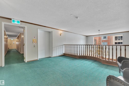 Empty room featuring ornamental molding, carpet, elevator, and a textured ceiling - 203 35 Sir Winston Churchill Avenue, St. Albert, AB - Indoor Photo Showing Other Room