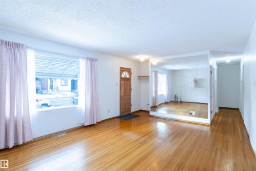Foyer entrance & living room with light wood-type flooring, a textured ceiling, and healthy amount of natural light - 9305 151 Street, Edmonton, AB - Indoor Photo Showing Other Room
