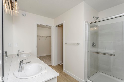Bathroom with double vanity, a walk in closet, light wood-style flooring, and a shower stall - 5111 Kinney Way Sw, Edmonton, AB - Indoor Photo Showing Bathroom