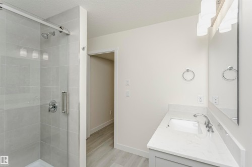 Full bath featuring vanity, a shower stall, light wood-style floors, and a textured ceiling - 5111 Kinney Way Sw, Edmonton, AB - Indoor Photo Showing Bathroom