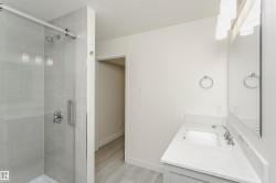 Full bath featuring vanity, a shower stall, light wood-style floors, and a textured ceiling - 