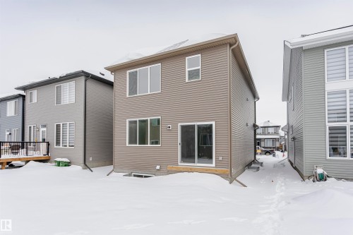 Snow covered house with a wooden deck - 5111 Kinney Way Sw, Edmonton, AB - Outdoor With Exterior