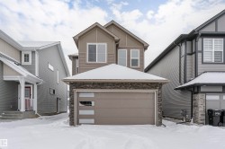 View of front of home featuring stone siding, a garage, an outdoor structure, and board and batten siding - 