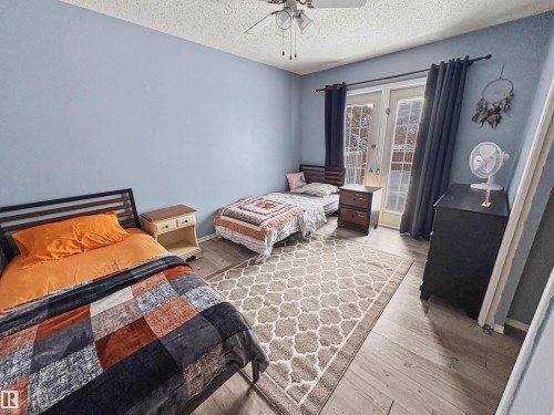 Bedroom with light wood-style floors, access to exterior, french doors, ceiling fan, and a textured ceiling - 4602 42 Avenue, Bonnyville Town, AB - Indoor Photo Showing Bedroom