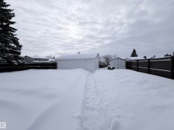 Yard layered in snow featuring a fenced backyard and an outbuilding - 