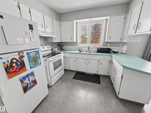 Kitchen with white appliances, light countertops, white cabinets, and a textured ceiling - 4602 42 Avenue, Bonnyville Town, AB - Indoor Photo Showing Kitchen With Double Sink