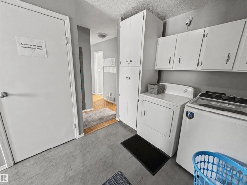 Laundry room with a textured ceiling, washing machine and clothes dryer, and cabinet space - 4602 42 Avenue, Bonnyville Town, AB - Indoor Photo Showing Laundry Room