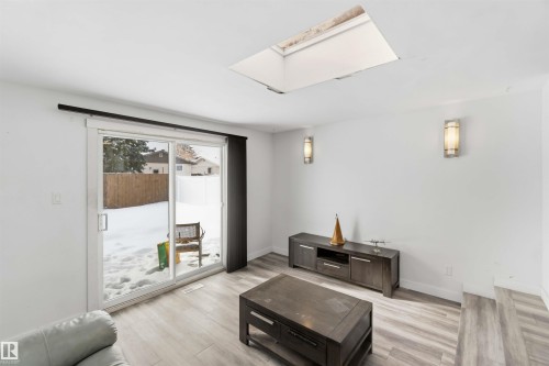 Living room featuring light wood-type flooring and a skylight - 11615 150 Avenue, Edmonton, AB - Indoor