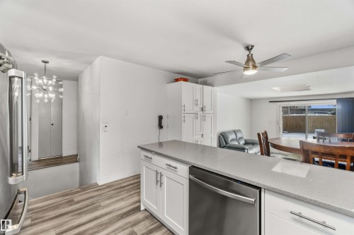 Kitchen featuring white cabinetry, stainless steel appliances, light stone counters, a ceiling fan, and light wood finished floors - 11615 150 Avenue, Edmonton, AB - Indoor Photo Showing Kitchen